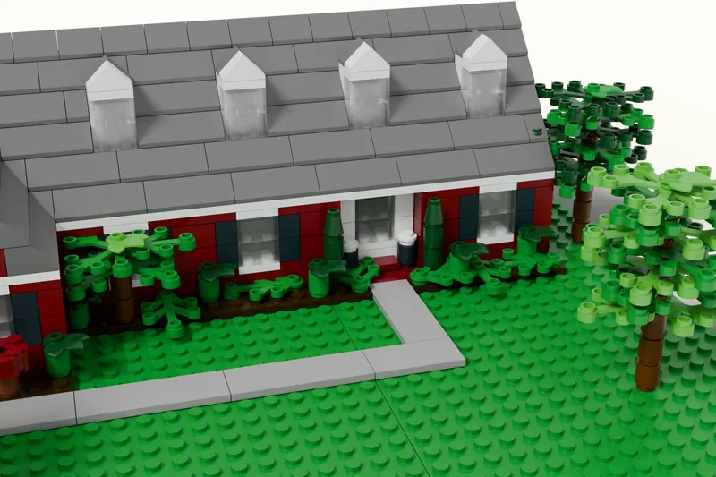 Close-up of a brick model’s front entry, dormers and garden beds